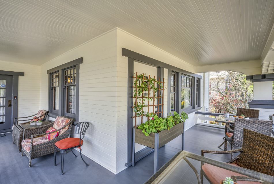 Exterior view of property's front porch with white walls, gray trim, gray flooring, and wicker patio furniture