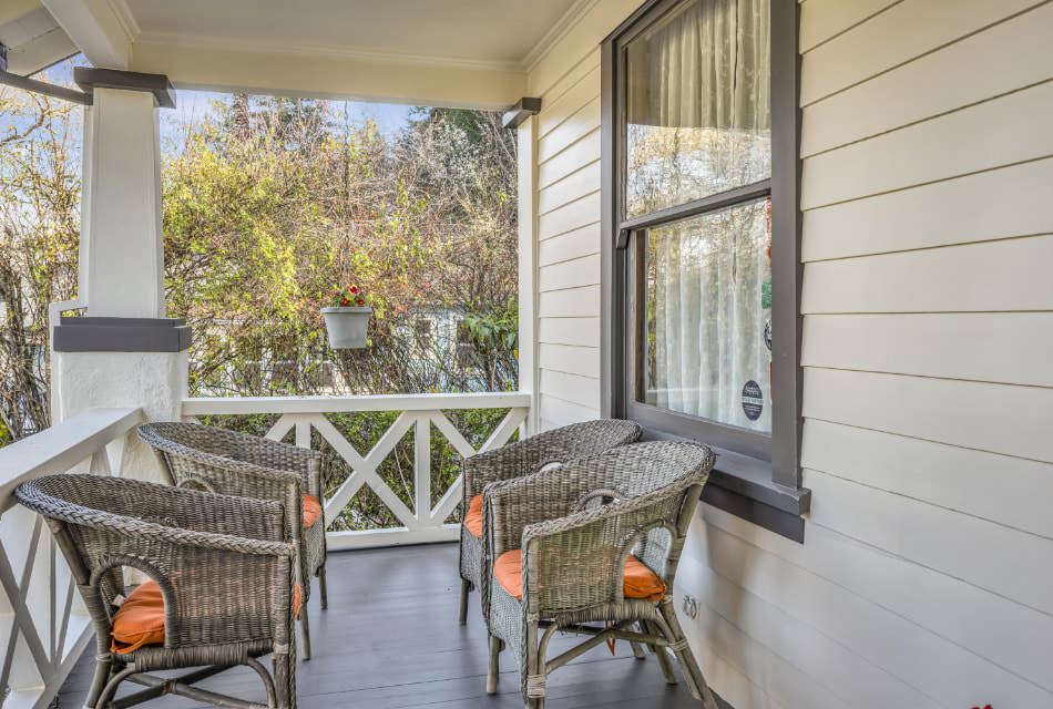 Exterior view of property's front porch painted white with gray trim and gray wicker patio furniture