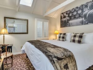 Bedroom with white walls, floral carpeting, white bedding, and dark wooden nightstands