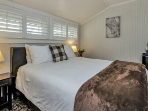 Bedroom with light gray walls, floral carpeting, white bedding, and black mini fridge