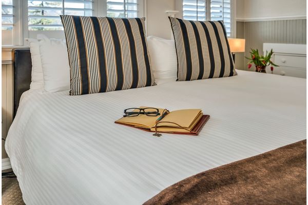 An open book and glasses on a King bed in the Palisades room at Craftsman Inn in Calistoga