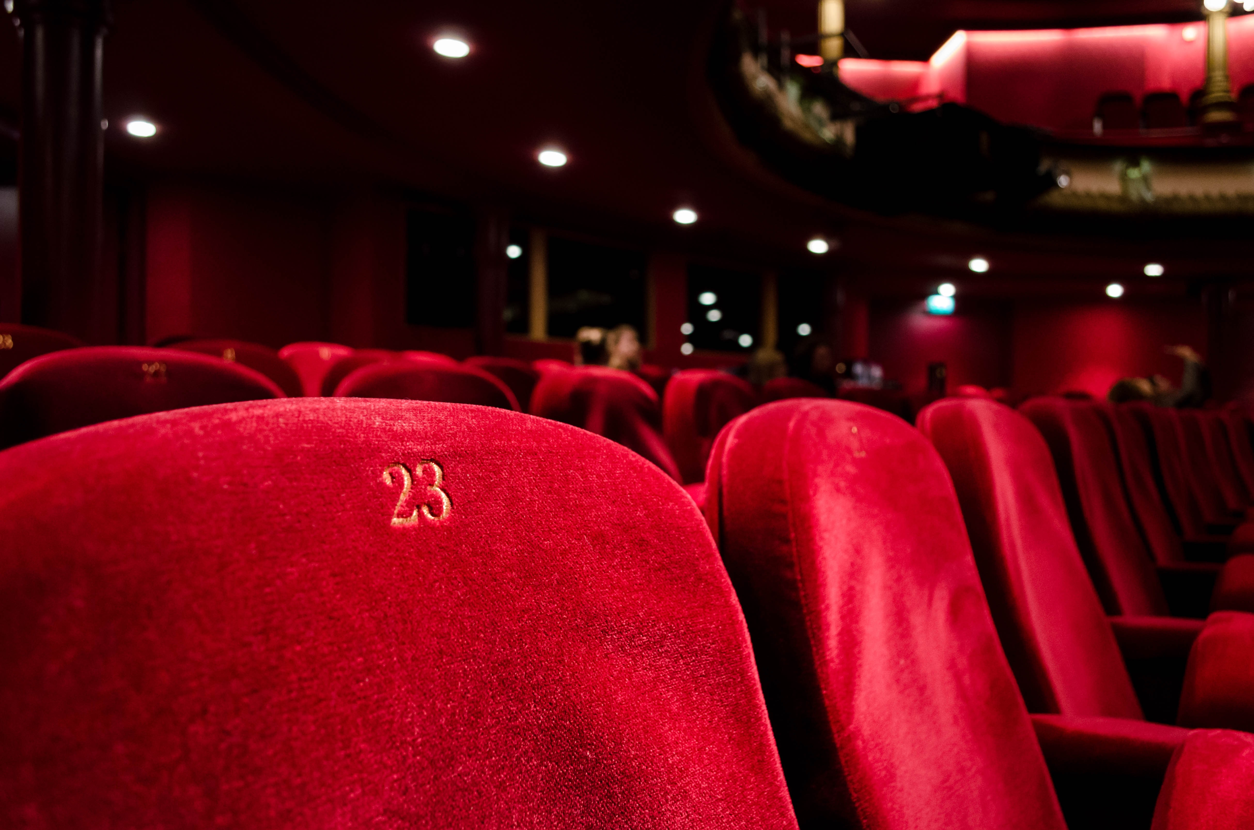 A dark theater with bold, red velvet seats.