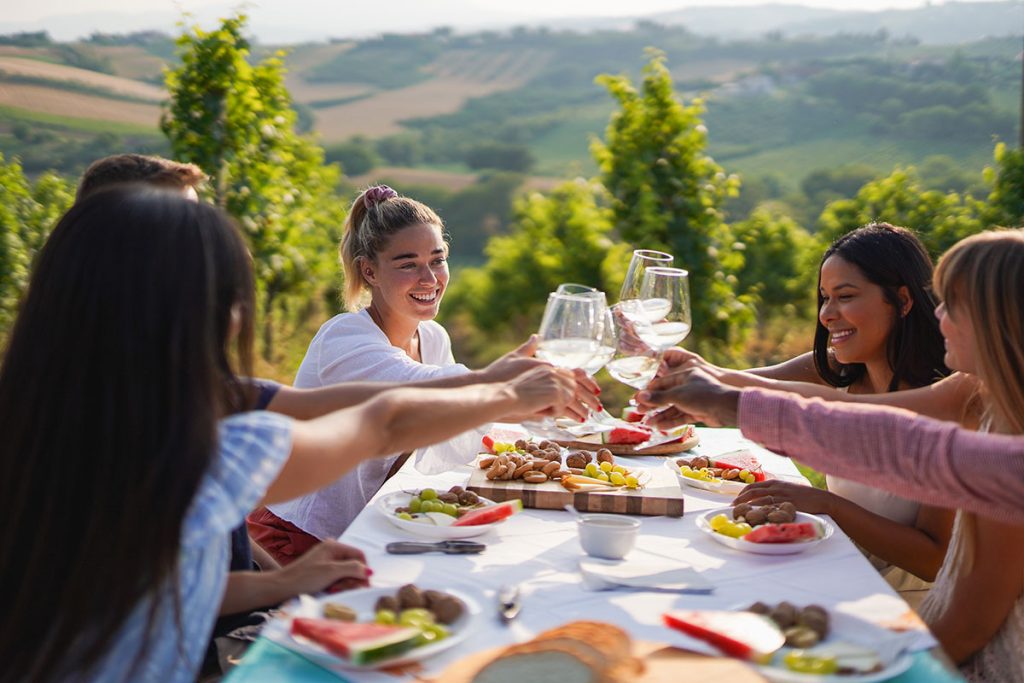 Wine tasting in the Napa Valley California a group of women outside clinking glasses.